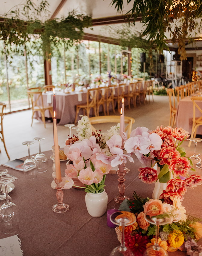 Mesas decoradas con flores en tonos rosas y rojizos
