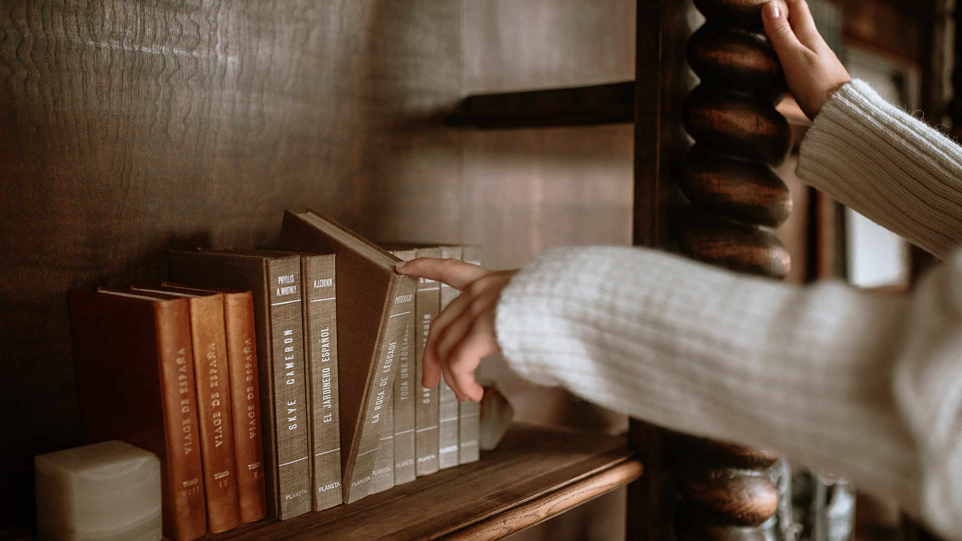 Detalle de la mano de una persona, cogiendo un libro de la biblioteca