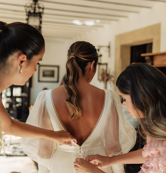 Amigas de la novia abrochándole el vestido
