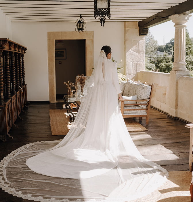 Novia con vestido de cola en el porche del palacio