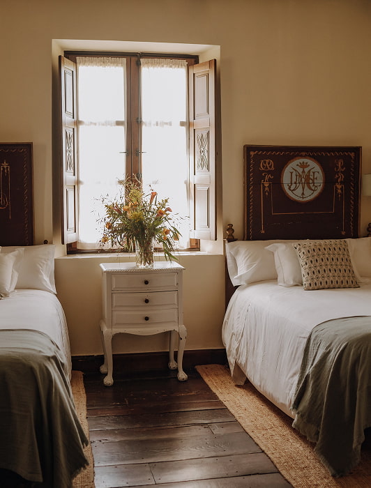 Habitación con dos camas individuales separadas por una mesita de noche blanca