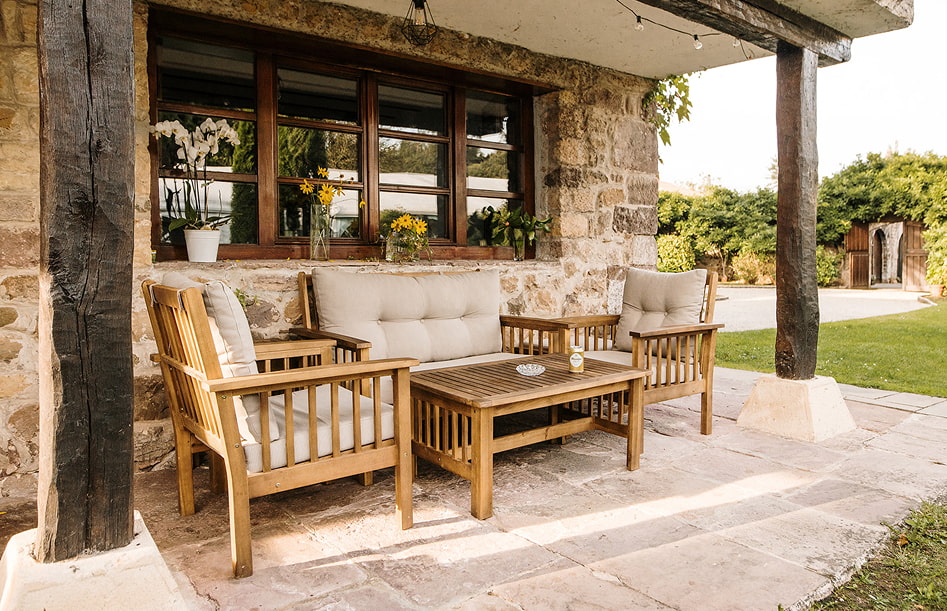 Porche exterior con mobiliario de madera y vistas a los jardines