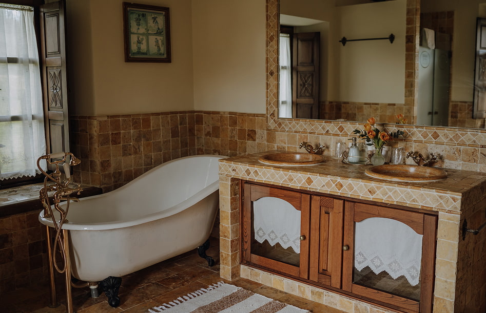 Baño con bañera de estilo victoriano y lavabo doble