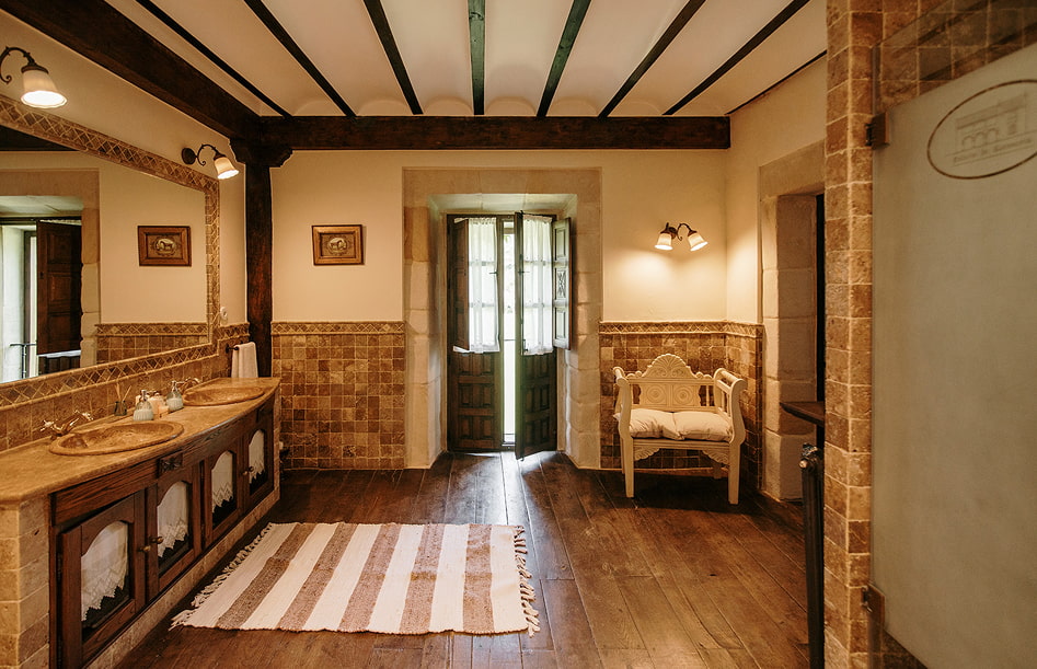 Baño con lavabo doble y butaca al fondo